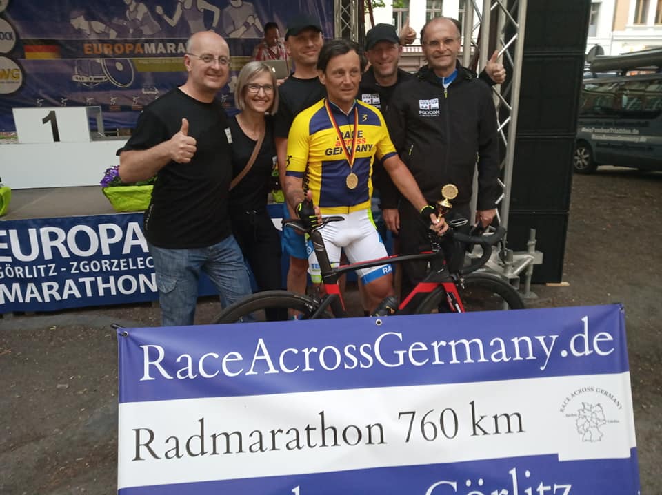 Skupinska slika na raf s kolesom in napisom Race Across Germany v ospredju
