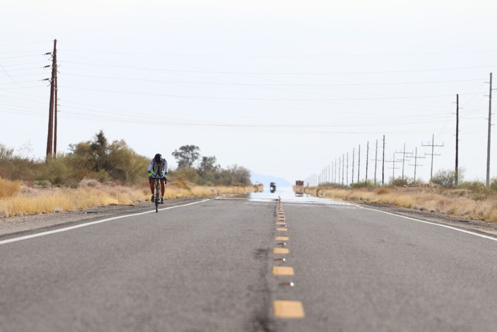 Neskončna ravnina z kolesarjem v ospredju in avtom v ozadju
