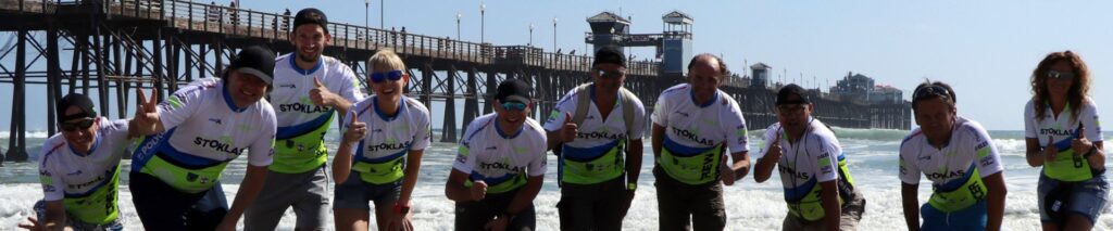 Skupinska slika na obali oceanside z morjem in pomolom v ozadju